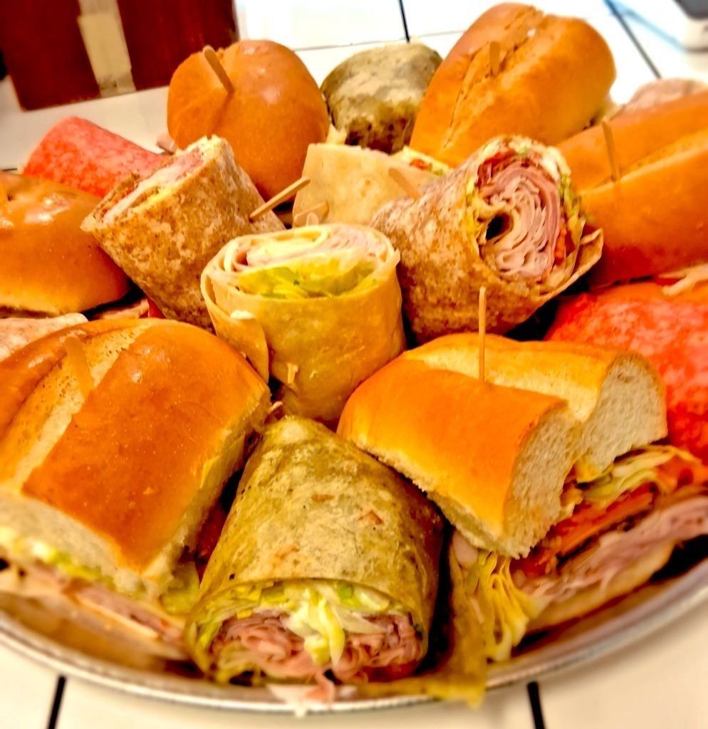A catering tray of cut subs and wraps held with picks